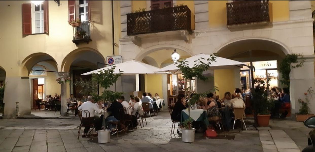 I tavoli della Trattoria Alla Cisterna sotto i portici di Piazza della Cisterna, di sera